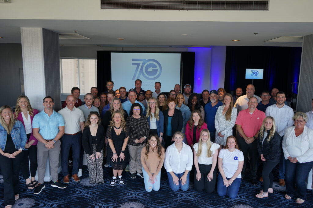 A large group photo of all of the executive team and loan officers in front of Gershman Mortgage's 70th Anniversary logo. 